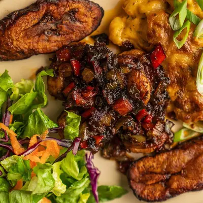 Jerk chicken with scallions and peppers, green salad and fried plantains.