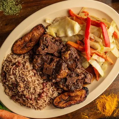 Oxtails dinner with cabbage, plantains, and rice and peas.