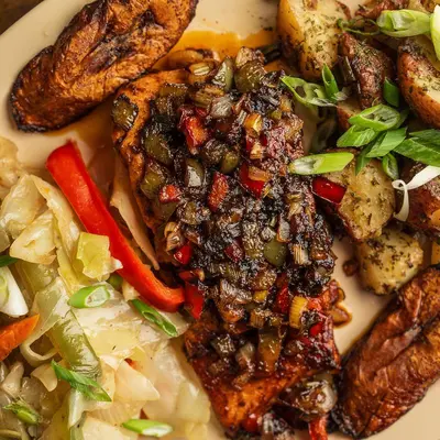 Jerk chicken with scallions and peppers over cabbage, with skillet potatoes and fried plantains.