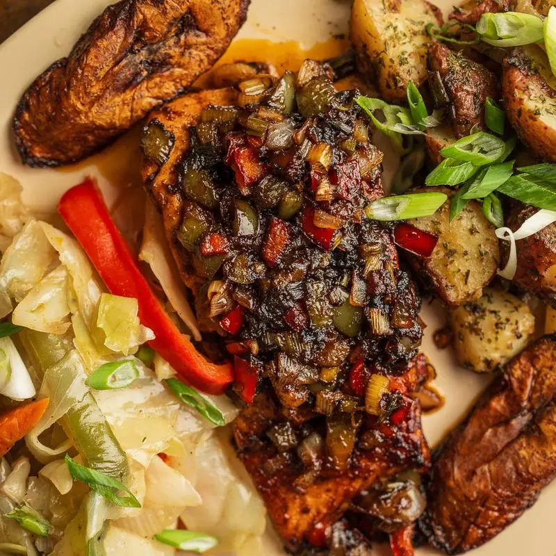 Jerk chicken with scallions and peppers over cabbage, with skillet potatoes and fried plantains.