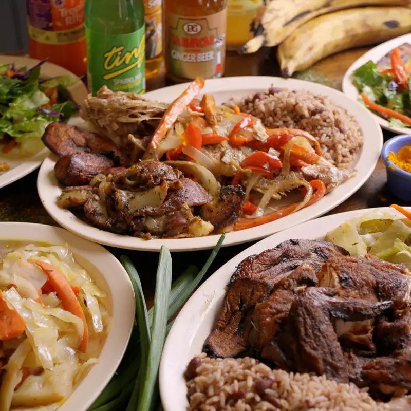 Curry goat and jerk chicken plates side by side with rice and peas and cabbage.