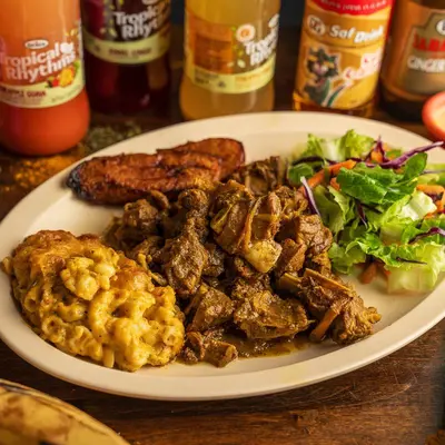 Curry goat with jalapeno mac and cheese, salad and fried plantains.