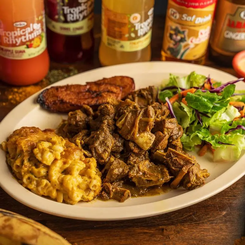 Curry goat with jalapeno mac and cheese, salad and fried plantains.