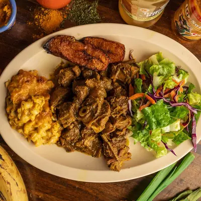 Jerk chicken with skillet potatoes, cabbage and fried plantains.