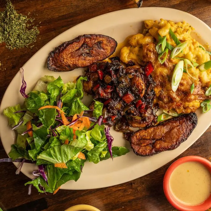 Curry goat with jalapeno mac and cheese, green salad and fried plantains.