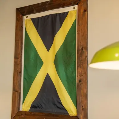 The Jamaican flag hanging in a wooden frame on the wall of the restaurant.